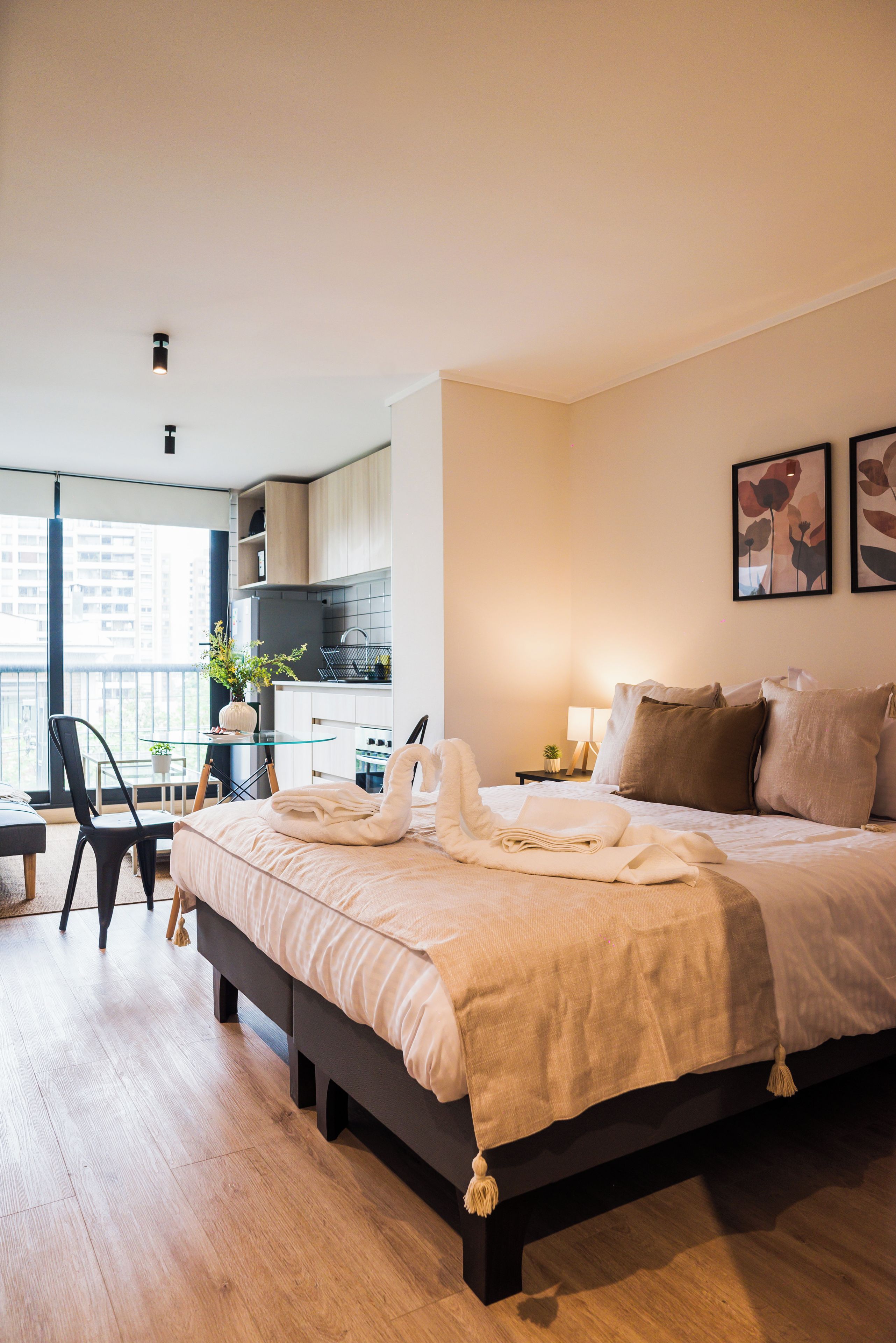 A modern bedroom with a large bed, a desk, and a view of the city.