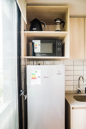 A compact kitchen with a refrigerator, microwave, and a coffee maker on a shelf. - Sunny Studio in Nunoa for 3 Guests (Ñuñoa)