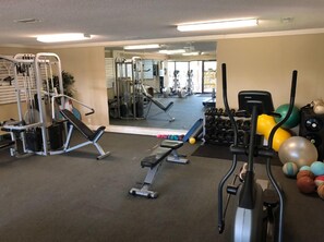 A gym with various exercise equipment, including a bench press, dumbbells, and exercise balls. - NEW Hilton Head Beach & Tennis Resort Building B Ocean Villa! (Hilton Head)