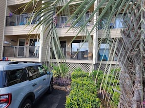 A multi-story building with balconies, a parked car, and a palm tree. - NEW Hilton Head Beach & Tennis Resort Building B Ocean Villa! (Hilton Head)