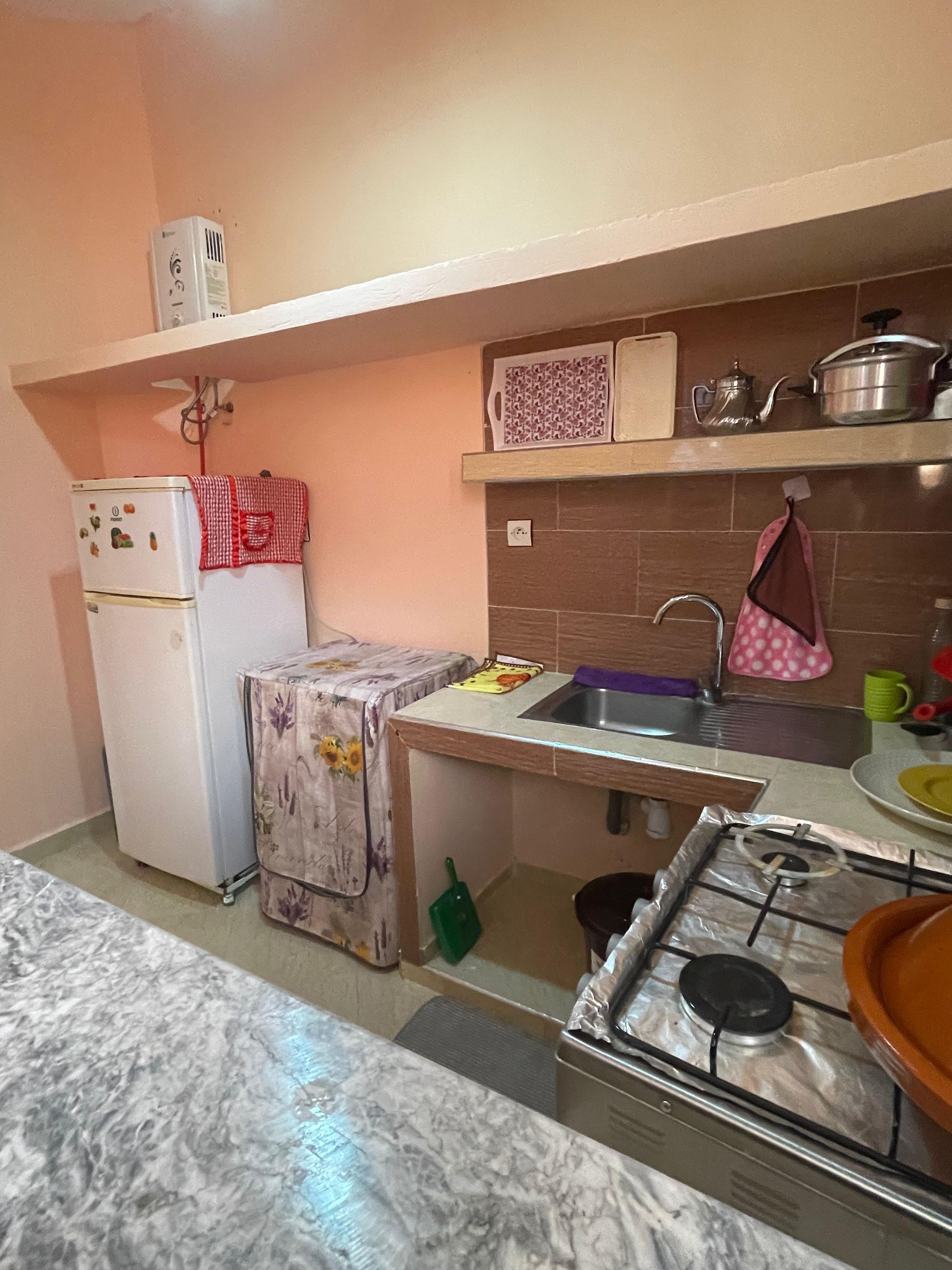 A compact kitchen with a refrigerator, a stove, a sink, and a countertop.