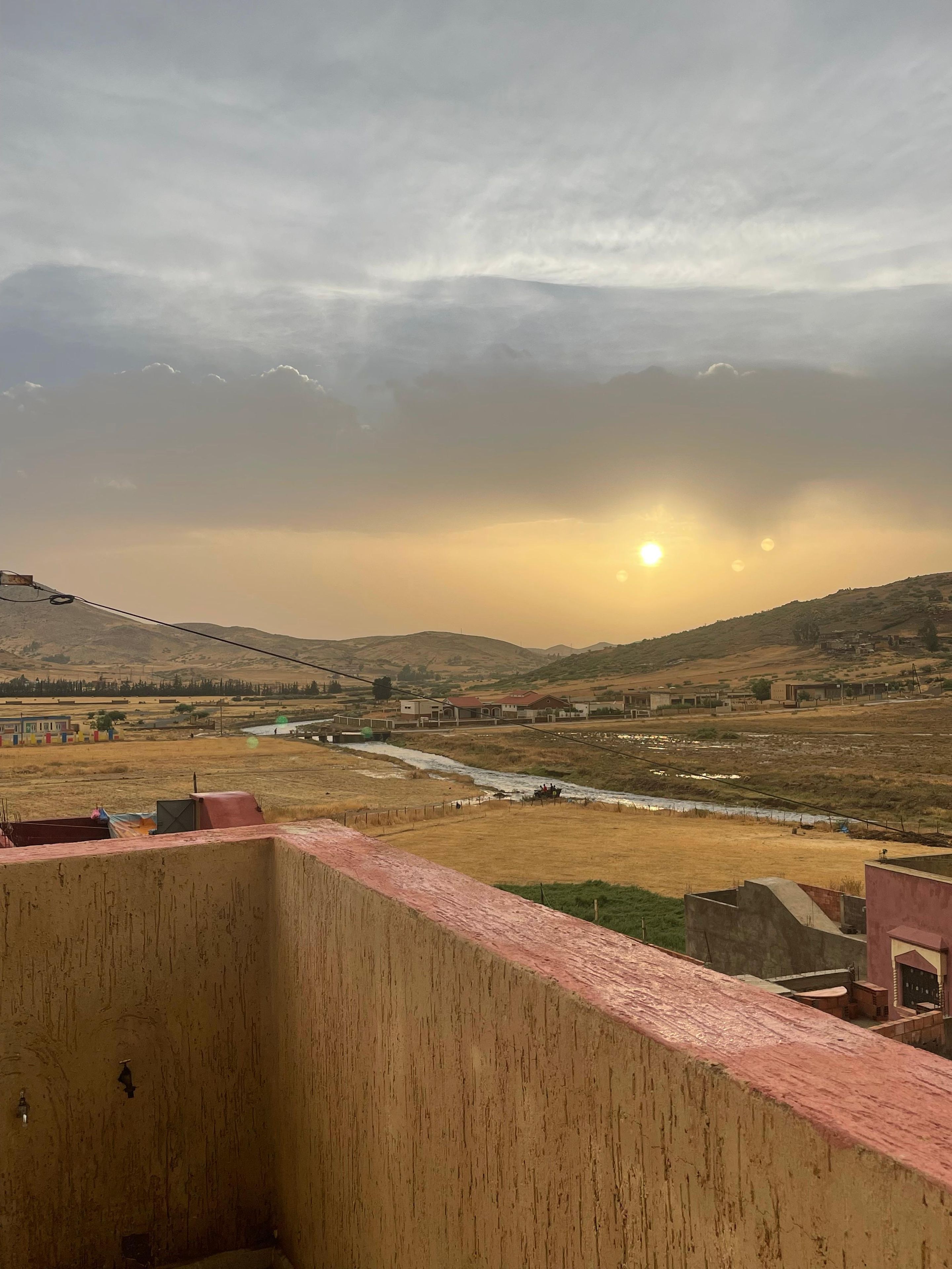 Vista desde un balcón sobre un río, con edificios y colinas a lo lejos.