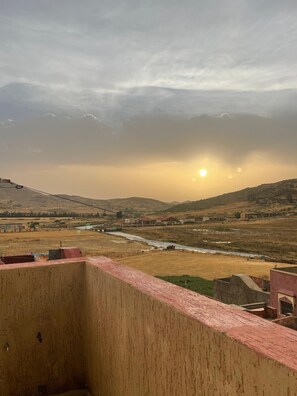 Vista desde un balcón sobre un río, con edificios y colinas a lo lejos.