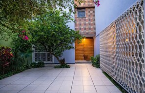 A courtyard with a tiled floor, a wooden door, and a decorative wall. - Casa Guapa | Family Residence with Parking (Oaxaca de Juárez)