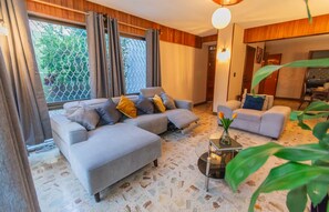 A modern living room with a sectional sofa, a smaller sofa, and a coffee table. - Casa Guapa | Family Residence with Parking (Oaxaca de Juárez)