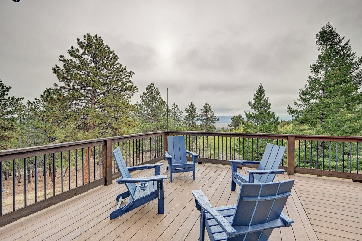 A deck with wooden flooring and a metal railing, surrounded by trees.