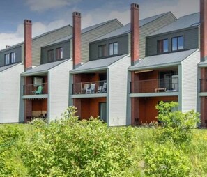 A row of modern multi-story buildings with balconies, likely residential apartments. - Burke Mountain Condo, Steps to Kingdom Trails (Burke)