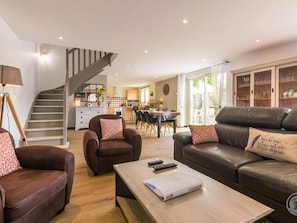 A modern living room with a sofa, armchairs, a coffee table, and a staircase leading to a kitchen. - Contemporary house near beach - 5 guests (Blainville-sur-Mer)