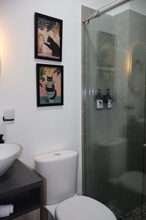 Un baño moderno con cabina de ducha de vidrio, un inodoro y dos lavamanos.