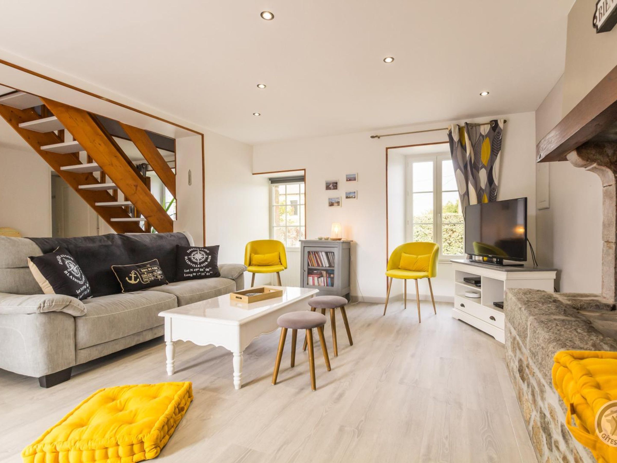 Een moderne woonkamer met een trap, een televisie, een boekenkast en een bank.