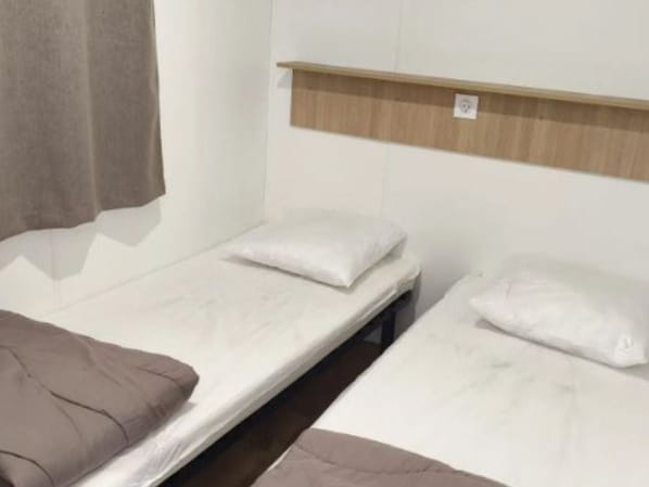 A single room with two beds, each with a pillow and a blanket. - Mobile home with AC - 4 guests (Baudreix)