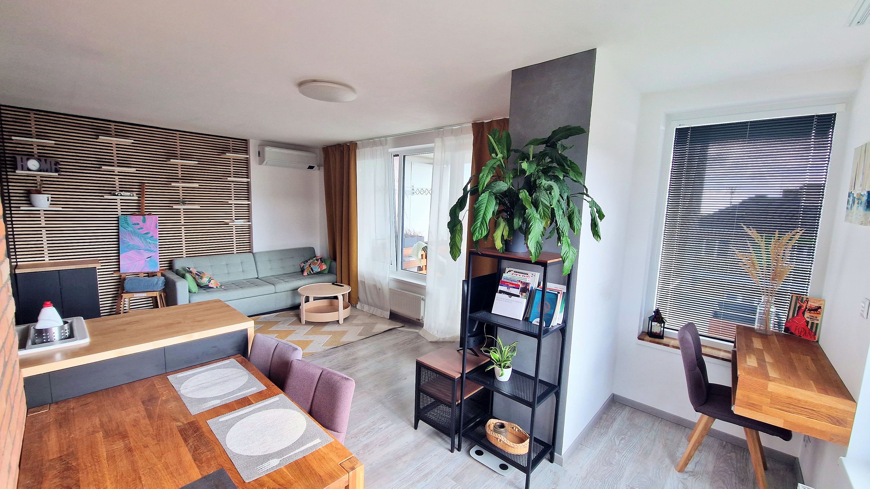 En moderne stue med sofa, sofabord og et spiseområde med et træbord og stole.