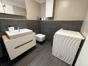 Ein modernes Badezimmer mit Waschbecken, Toilette und Waschmaschine in Weiß.