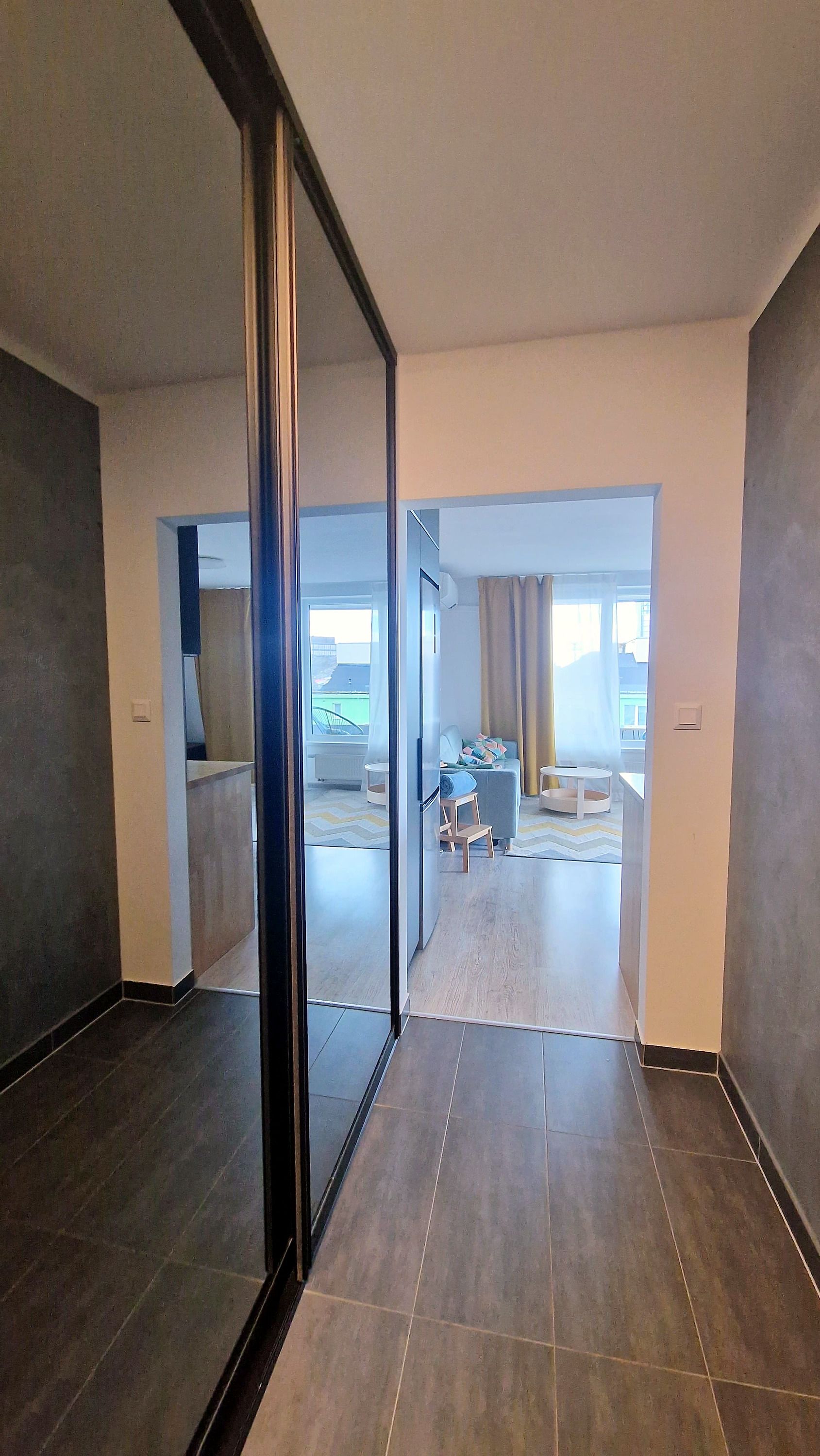 A modern interior with a large sliding glass door leading to a living area with a sofa and a dining table.
