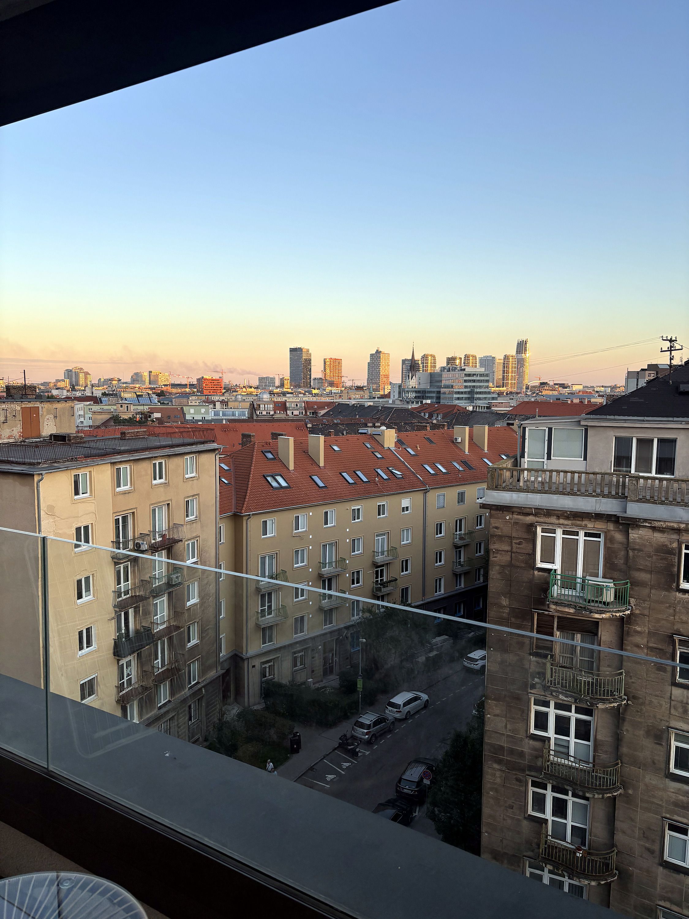 Eine Stadtansicht mit mehrstöckigen Gebäuden, einige davon mit Balkonen, und einem klaren Himmel.