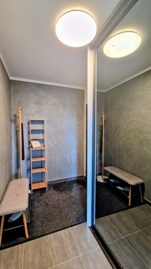 Ein Zimmer mit grauem Teppich, einer Holzbank, einem kleinen Hocker und einer an der Wand stehenden Holzleiter.