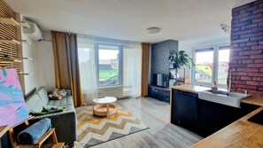 Ein modernes Wohnzimmer mit einer Couch, einem kleinen runden Tisch und Blick ins Freie.