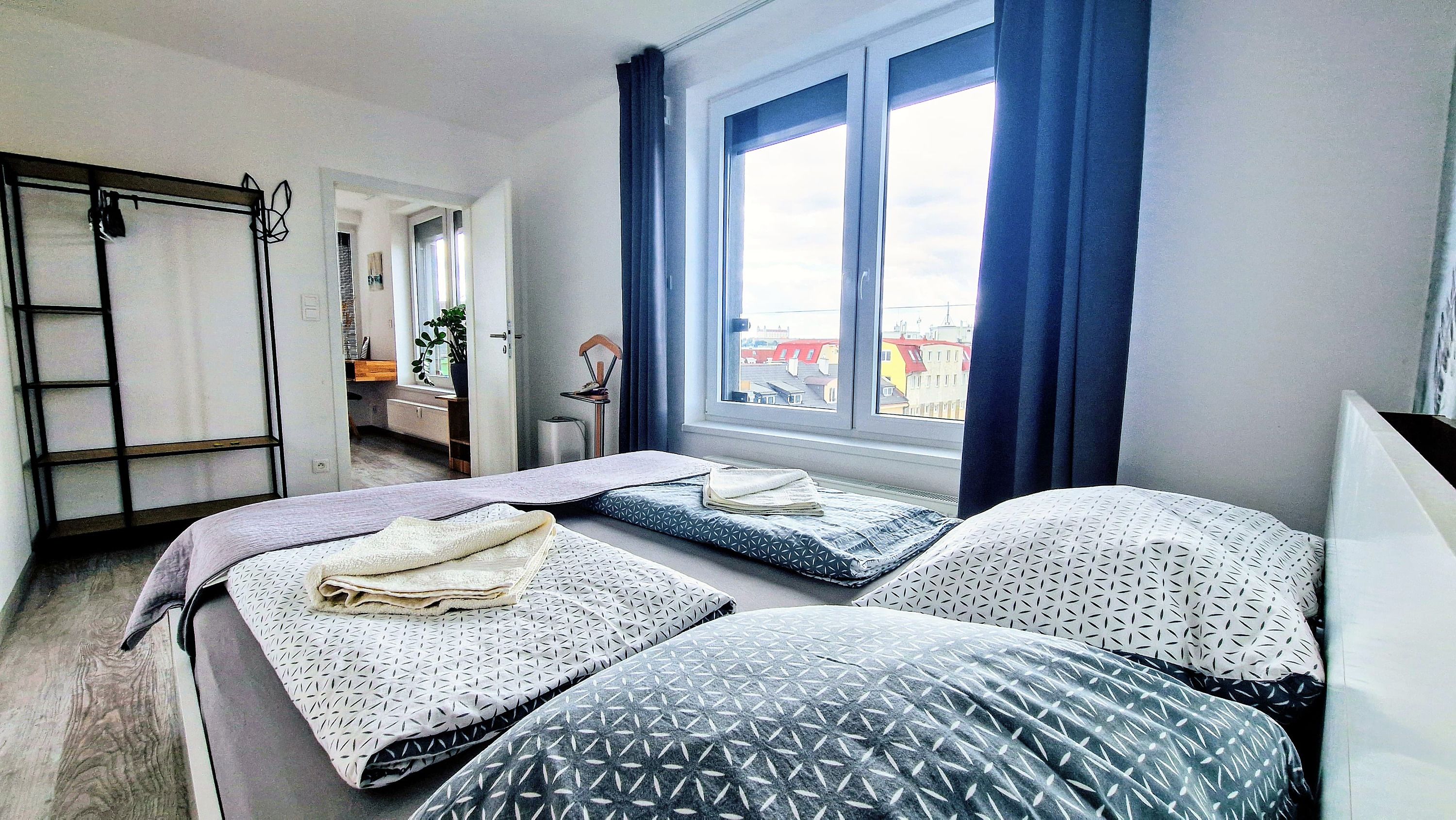 A bedroom with two beds, a window with curtains, a desk, and a chair.