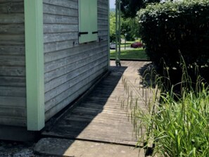 A wooden house with a green door and a narrow wooden pathway leading to it. - Cozy chalet with terrace - 4 guests (Baudreix)