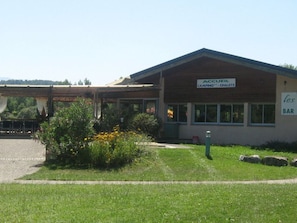 A building with a sign that reads "ACCUEIL CAMPING CHALETS" and another sign that says "les BAR". - Cozy chalet with terrace - 4 guests (Baudreix)