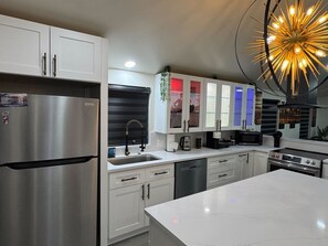 Una cocina moderna con electrodomésticos de acero inoxidable, armarios blancos y una isla central.