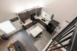Eine moderne Küche mit Kochinsel, eingebauten Geräten und einem Essbereich mit Treppe.