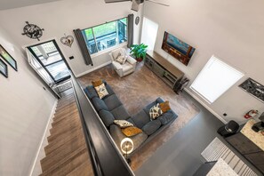 A spacious living area with a large sectional sofa, a dining table, and a staircase leading to an upper floor. - 3 bedrm house nestled on 5 acres in Sevierville w/hot tub, private walking trail (Sevierville)