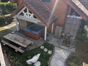 Ein Holzhaus mit Whirlpool, Grill und Vogel-Skulptur.
