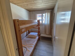 A narrow room with a bunk bed, a small bench, and a door. - Spacious apartment, parking - 7 guests. Slope view (Arâches-la-Frasse)