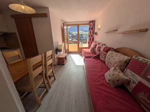 A cozy living area with a wooden sofa, a wooden table, and a television. - Apartment, pets OK, parking - mountain view (Plagne Soleil)