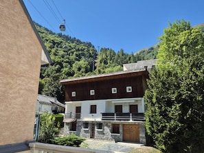 Un edificio de dos pisos con fachada de piedra, contraventanas de madera y un balcón.