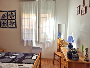 A bedroom with a bed, a desk with a lamp, a chair, and a wall with framed pictures. - Apartment mountain view, terrace - 4 guests (Cauterets)