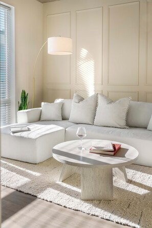 Ein modernes Wohnzimmer mit einer Eckcouch, einem Couchtisch und einer Stehlampe.