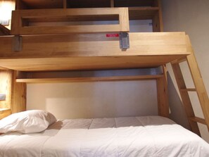 Ein Etagenbett mit einer Leiter, einem Kopfkissen und einem Holz-Kopfteil.