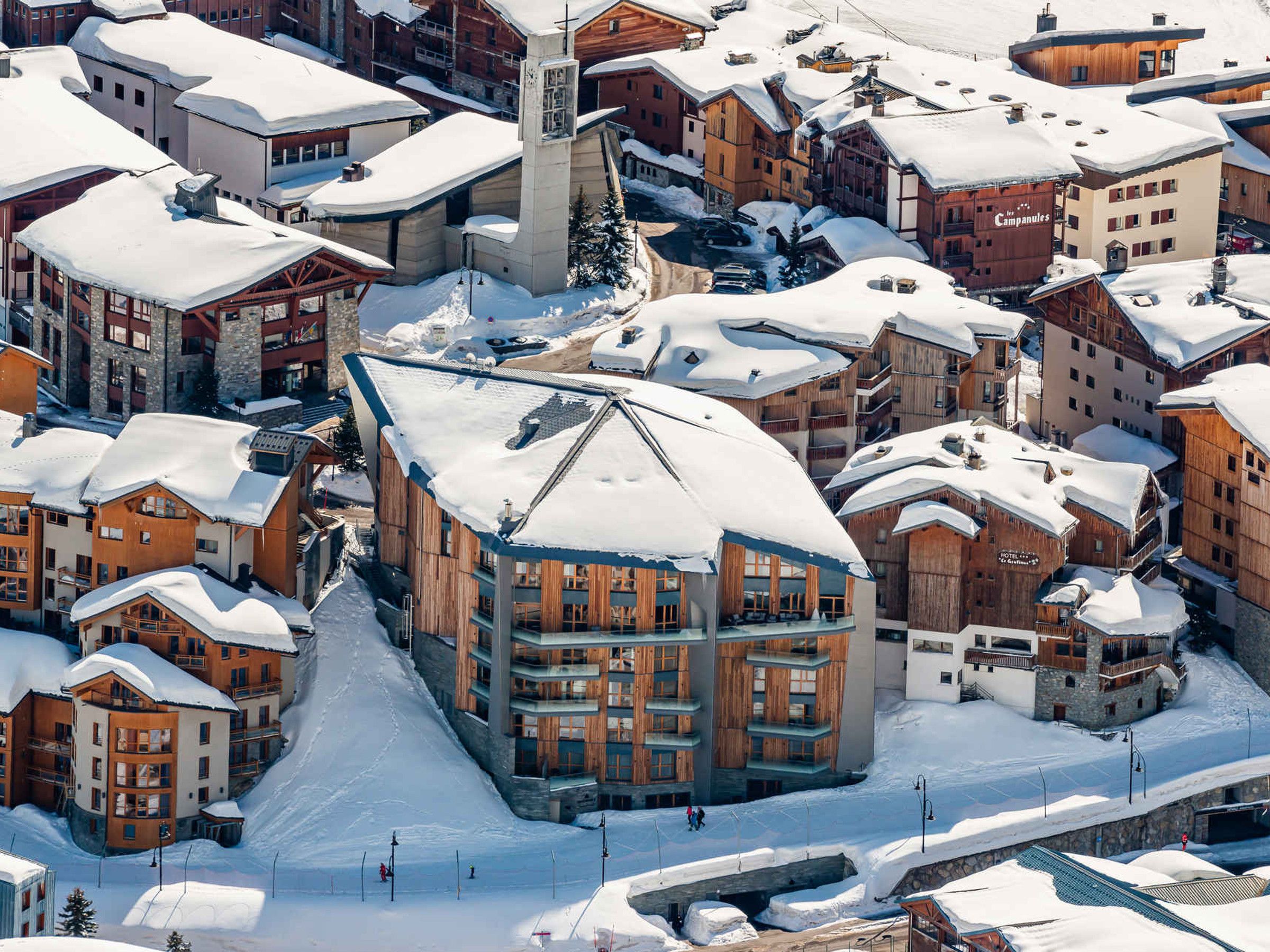 A snow-covered mountain town with wooden buildings and a ski lift.