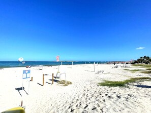 Una playa de arena blanca, cielo azul despejado y mar tranquilo.