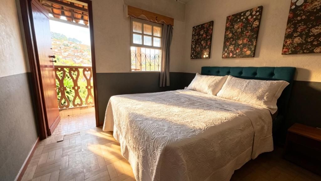 A bedroom with a bed, a window, and a view of a balcony.