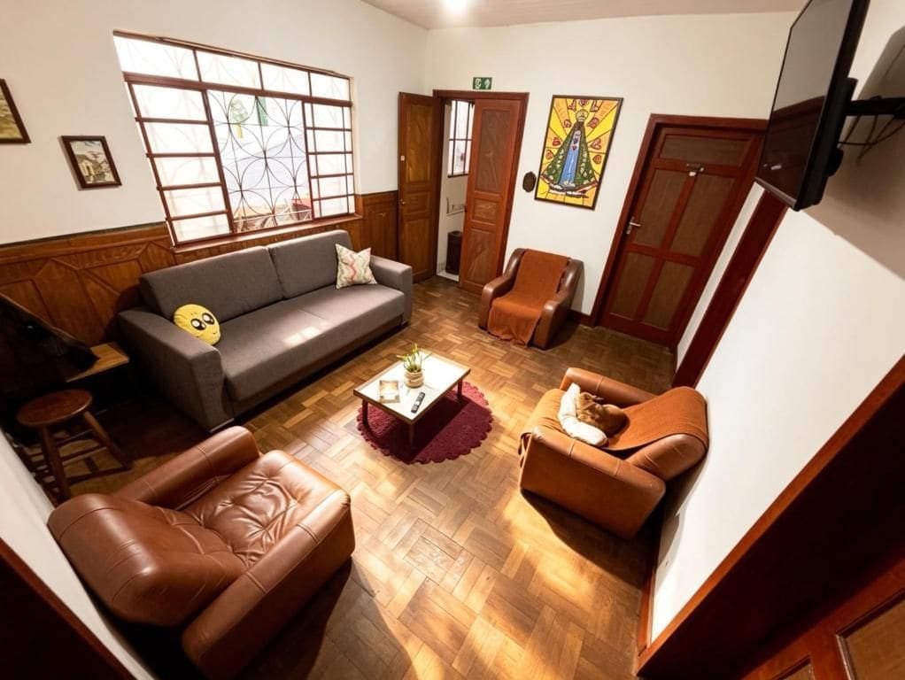 A room with a sofa, armchairs, a coffee table, and a television.