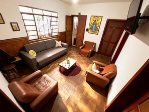 A room with a sofa, armchairs, a coffee table, and a television. - Nuh Hostel (Ouro Preto)