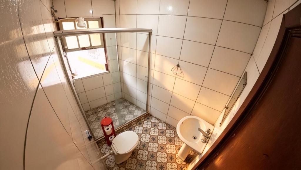 Et lille badeværelse med toilet, håndvask og bruseområde.