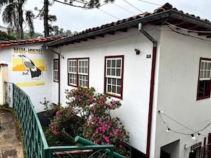 A hostel with a white exterior, red window frames, and a mural of a bird. - Nuh Hostel (Ouro Preto)