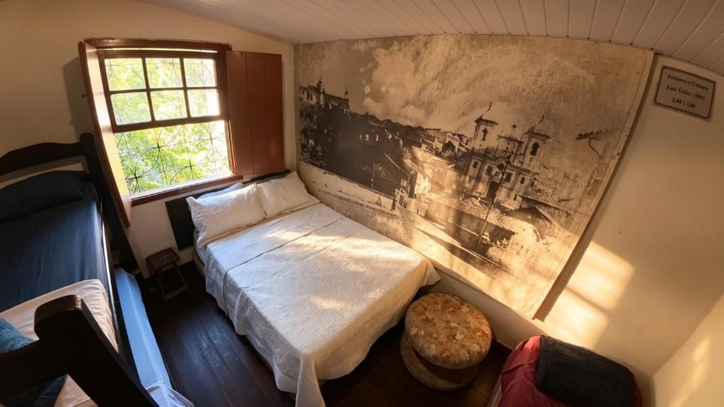 A room with a bed, a window, a tapestry, and a small stool.