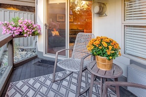 A balcony with a seating area, a potted plant with orange flowers, and a window with blinds. - Ski-in/Ski-out 1Bdrm Luxury Condo, Slps 4, 1st fl, The Aspens, Pool & hot tubs (Whistler)