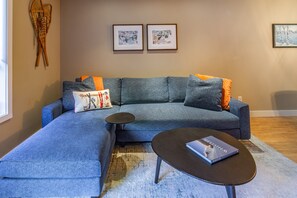 Un salon moderne avec un canapé d’angle, une table basse et deux tableaux encadrés accrochés au mur.