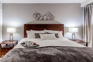 Une chambre d’hôtel avec un grand lit, deux tables de chevet, une tête de lit et une œuvre d’art décorative accrochée au mur au-dessus du lit.