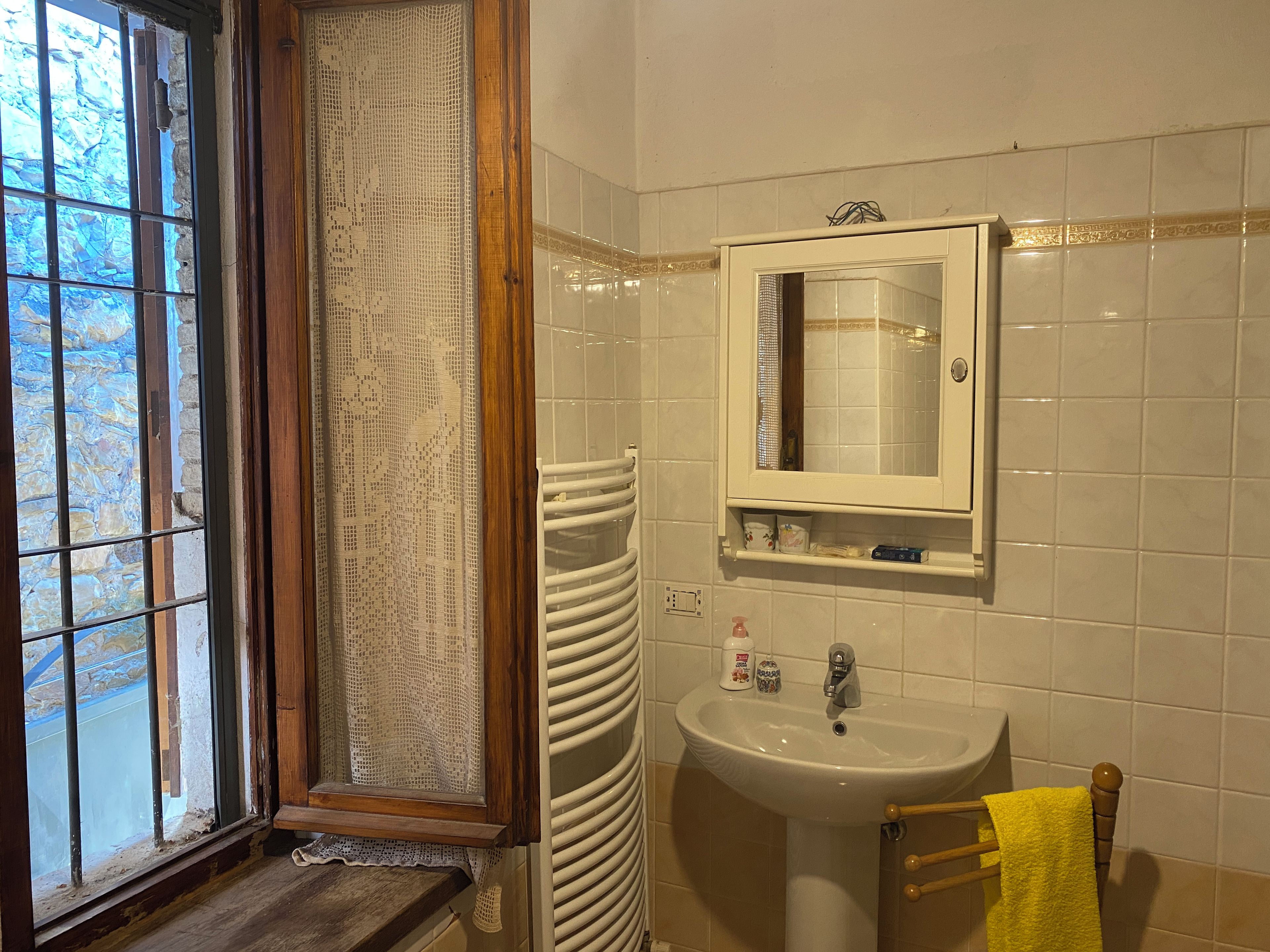 Un baño con ventana, un lavabo, un espejo y un perchero para toallas.