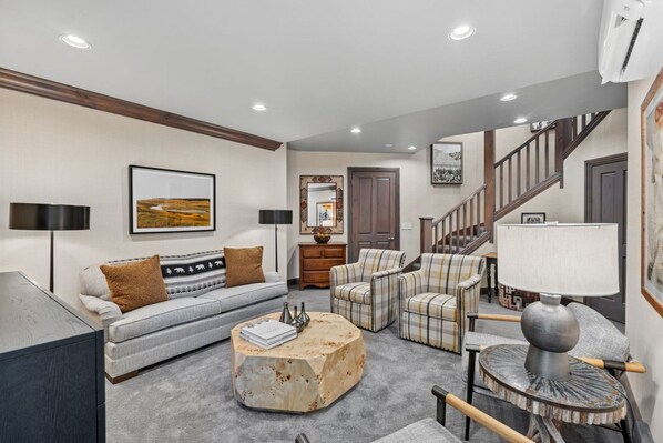 A living room with a sofa, armchairs, a coffee table, and a lamp. There is a staircase leading to another level. - Ski-In/Ski-Out Beaver Creek | Walk to Village (Beaver Creek)