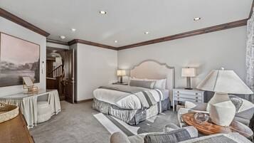 A hotel room with a bed, bedside tables, a desk, a chair, and a large window.