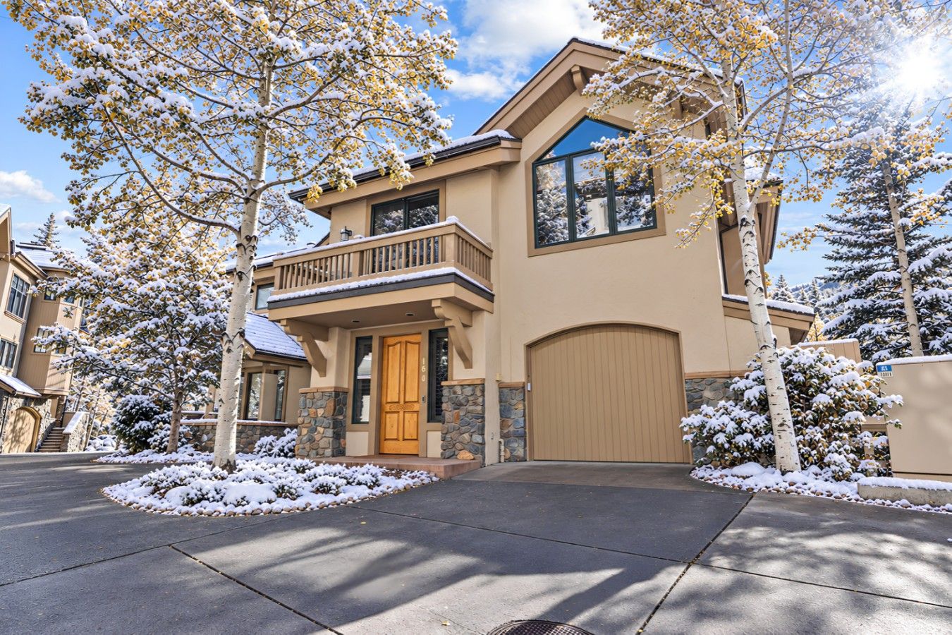 A two-story house with a stone facade, a wooden front door, and a garage.