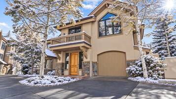 A two-story house with a stone facade, a wooden front door, and a garage.